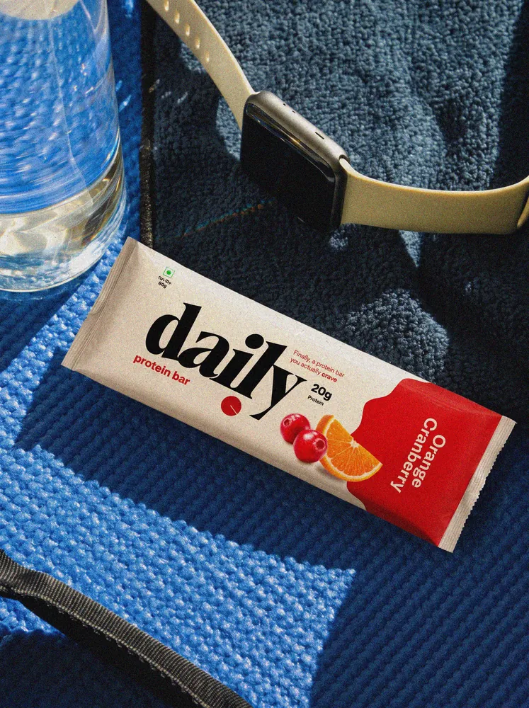 Orange Cranberry bar on a blue yoga mat beside a water bottle